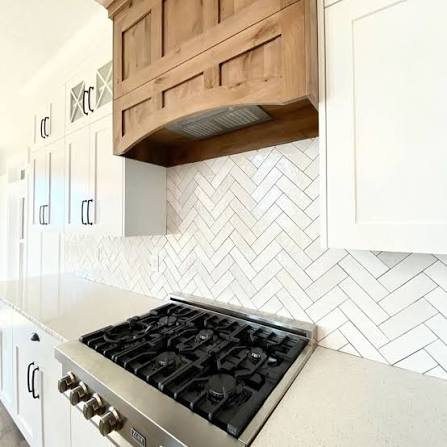 Herringbone tile backsplash with a custom wood hood