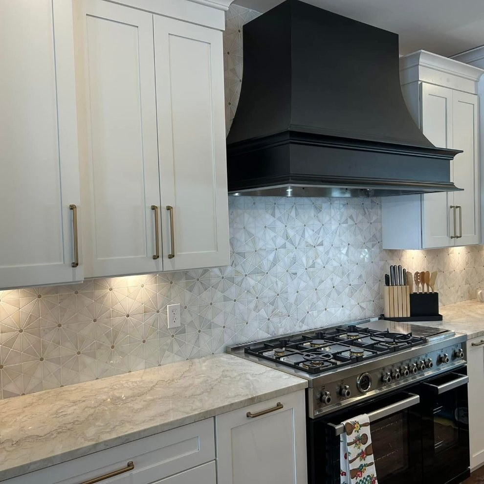 White kitchen with marble backsplash and black hood