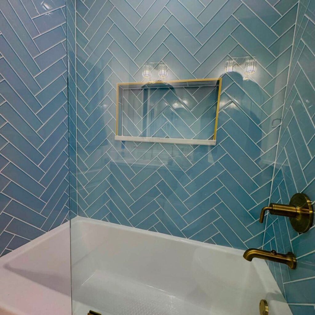 Blue herringbone tub surround with brass fixtures